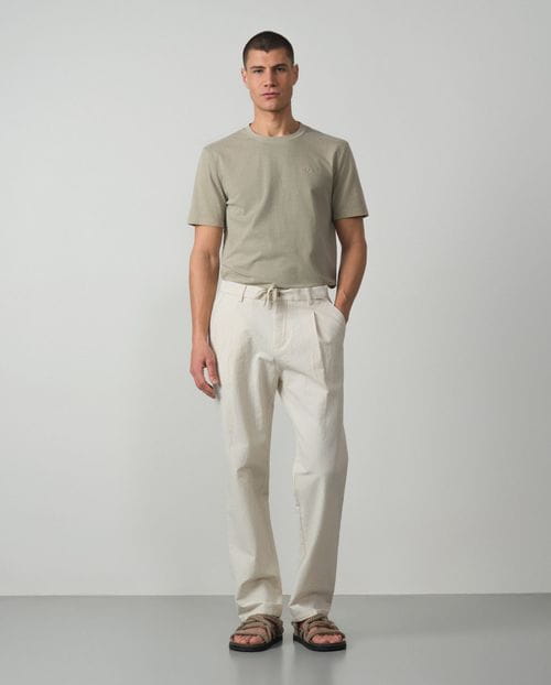 <p>Pantalón de una pinza con cordón y goma realizado en una raya fina de <em>seersucker</em></p>