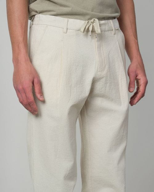 <p>Pantalón de una pinza con cordón y goma realizado en una raya fina de <em>seersucker</em></p>