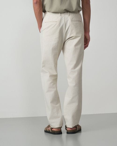 <p>Pantalón de una pinza con cordón y goma realizado en una raya fina de <em>seersucker</em></p>